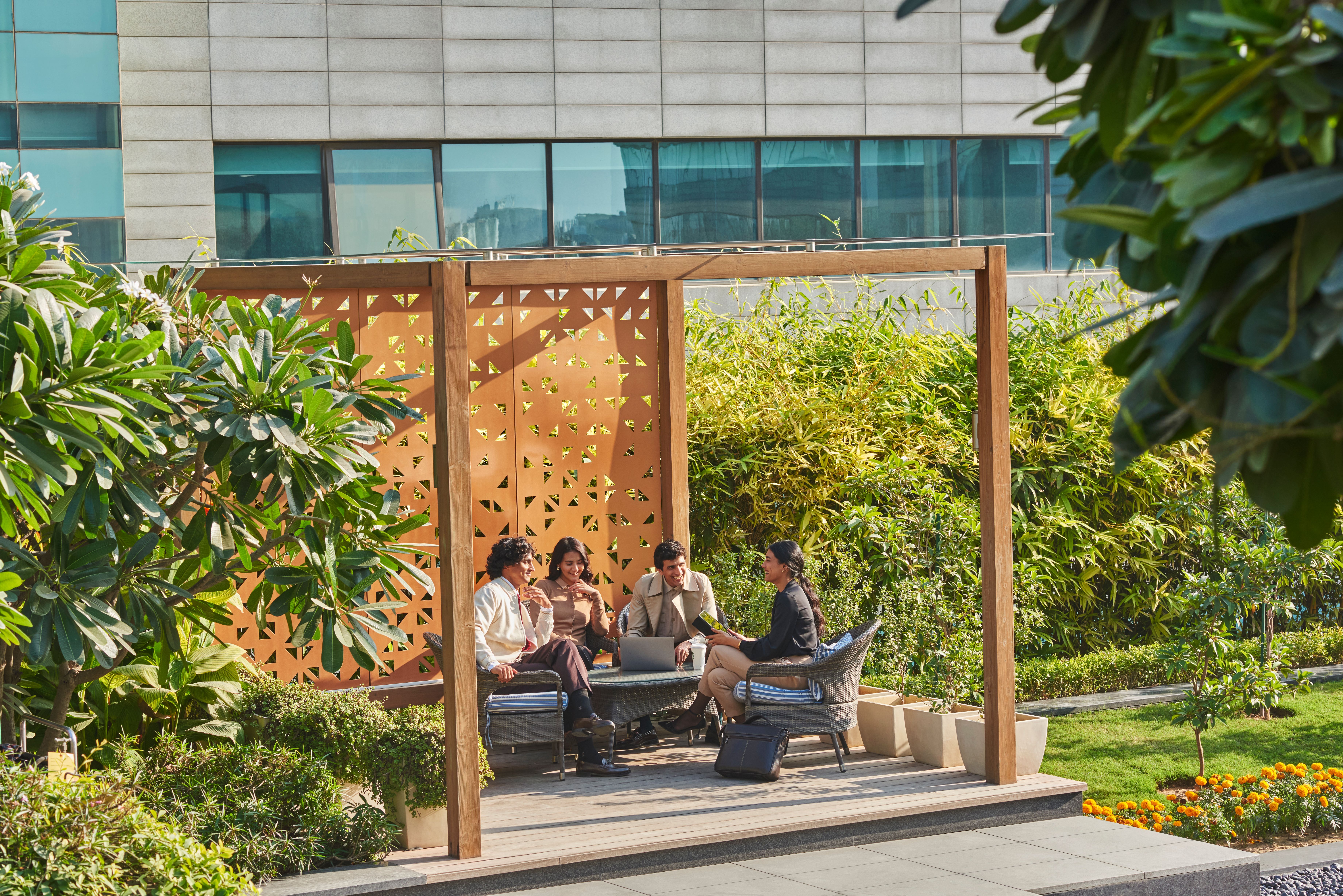 Luxury residential terrace with shaded cabanas and lush greenery. Modern Indian real estate.