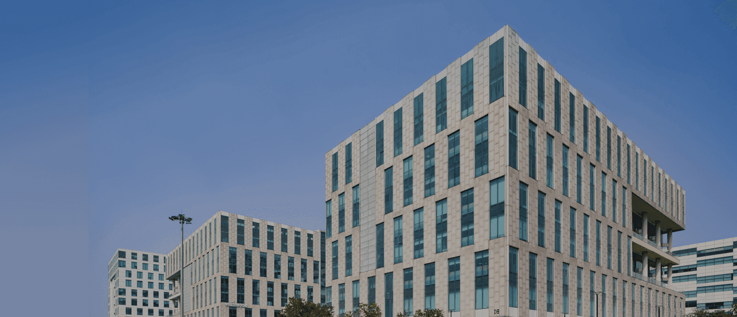 Modern office building exterior with glass facade and lush greenery.