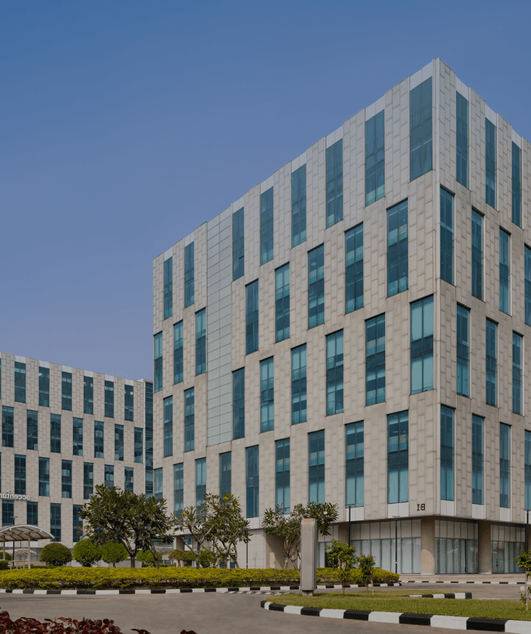 Modern office building exterior with glass facade and lush greenery.