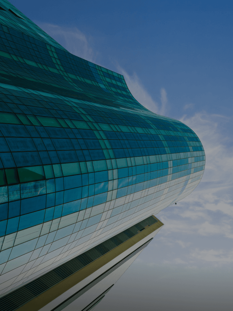 Modern office building exterior with glass facade and lush landscaping.