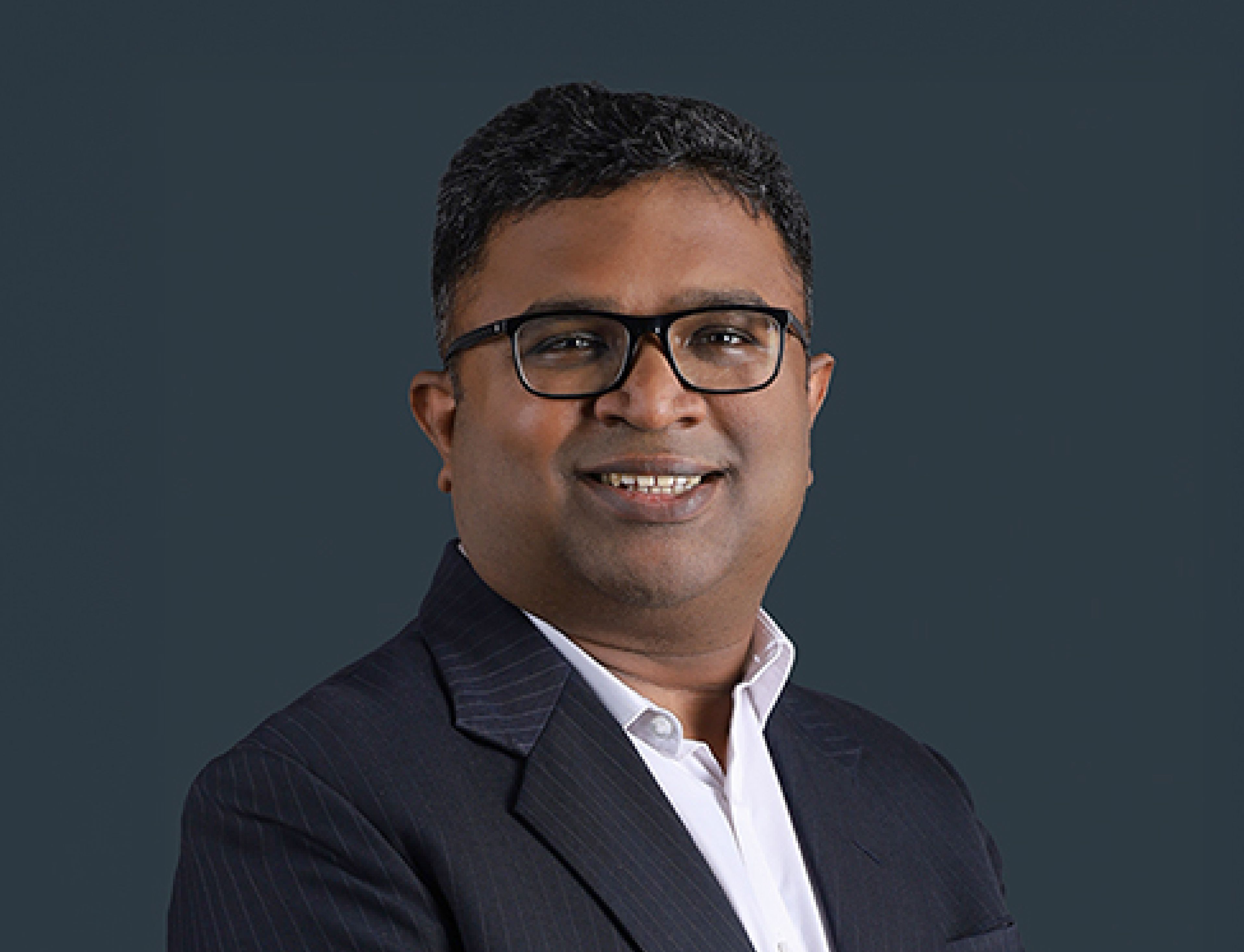 Man in suit smiling, professional headshot, Indian businessman, corporate portrait.